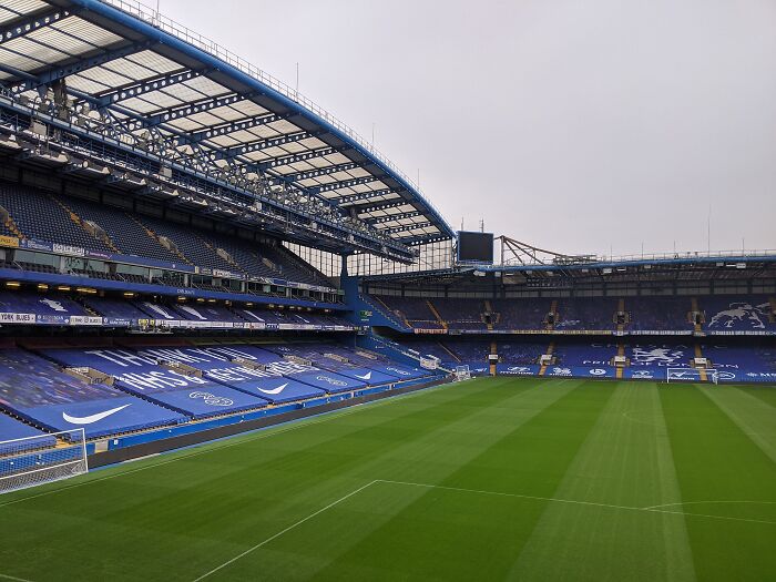 Soccer stadium with empty blue seats and a well-maintained green pitch, one of the cathedrals of soccer.