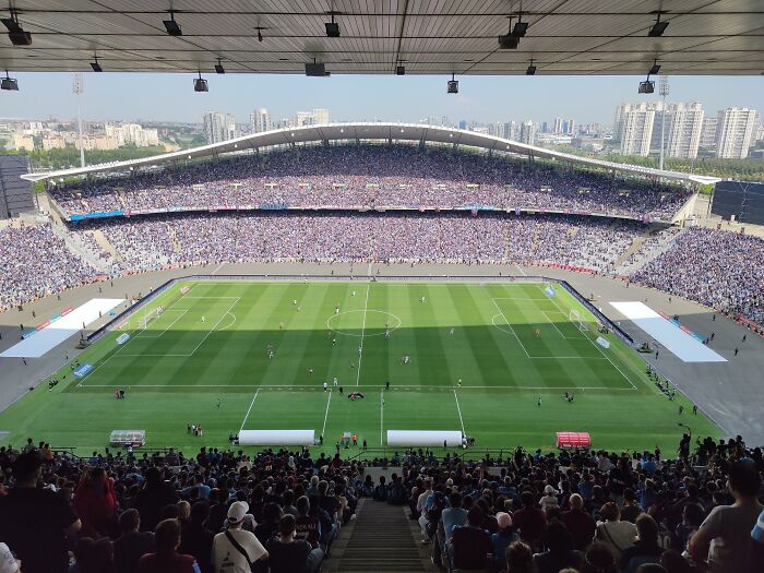 Packed soccer stadium with lively crowd watching a match on a bright day at one of the iconic cathedrals of soccer.