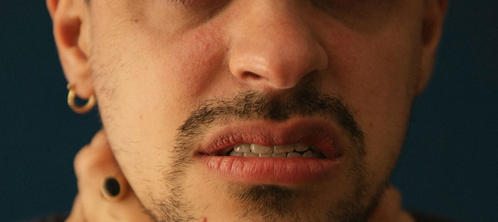 Man with visible burn scars and distressed expression, wearing a gold hoop earring, possibly experiencing a breakup. Man with visible burn scars and distressed expression, wearing a gold hoop earring, possibly experiencing a breakup.