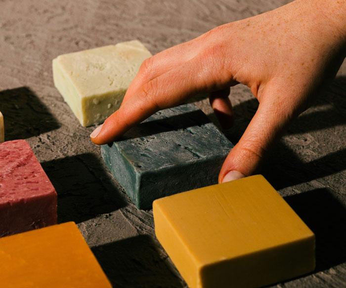 Hand reaching for colored soap bars on a textured surface, focusing on practical life-saving tips.
