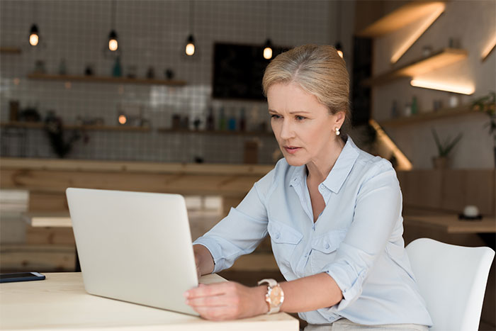 Woman in a light blue shirt concentrating on a laptop, pondering relationship decisions. Woman in a light blue shirt concentrating on a laptop, pondering relationship decisions.