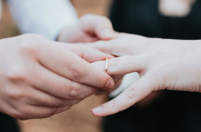 Hands placing a wedding ring on a finger, symbolizing a wedding ceremony. Hands placing a wedding ring on a finger, symbolizing a wedding ceremony.
