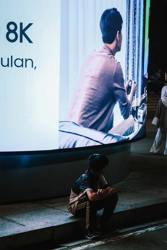 Person sitting in front of a large ad display captures the raw beauty of street life at night.