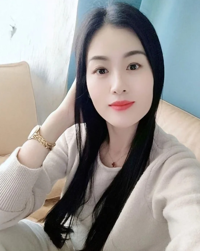 Pretty young 39-year-old grandma with long black hair, sitting on a beige couch, wearing a gold watch and white top. Pretty young 39-year-old grandma with long black hair, sitting on a beige couch, wearing a gold watch and white top.