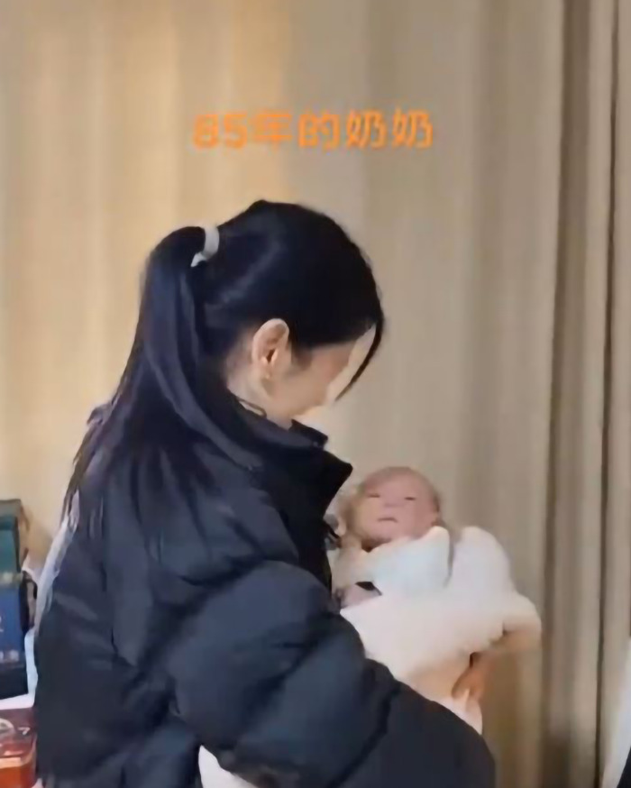 A "pretty young" grandma holds a baby, illustrating timeless generational bonds. A "pretty young" grandma holds a baby, illustrating timeless generational bonds.