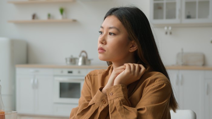 Young woman in a brown shirt sits thoughtfully in a modern kitchen, pondering wedding attire etiquette. Young woman in a brown shirt sits thoughtfully in a modern kitchen, pondering wedding attire etiquette.