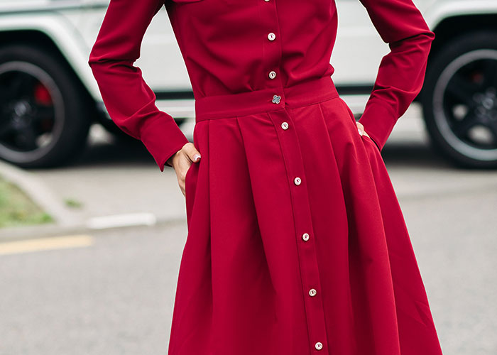 Woman in a red dress stands with hands on hips, in front of a car, emphasizing respect and Sweet 16 theme. Woman in a red dress stands with hands on hips, in front of a car, emphasizing respect and Sweet 16 theme.