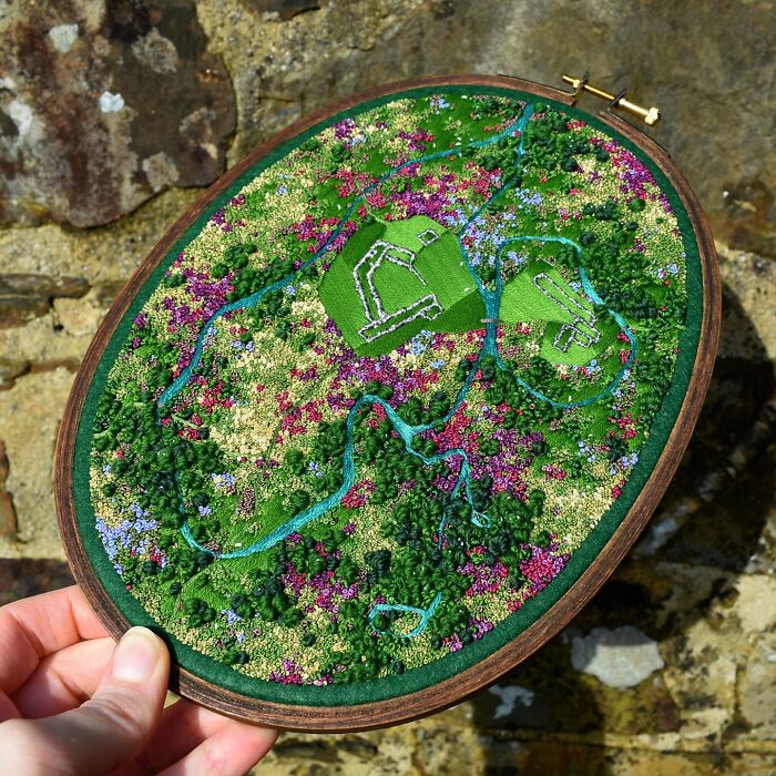 Landscape embroidery art showcasing vibrant fields and streams.