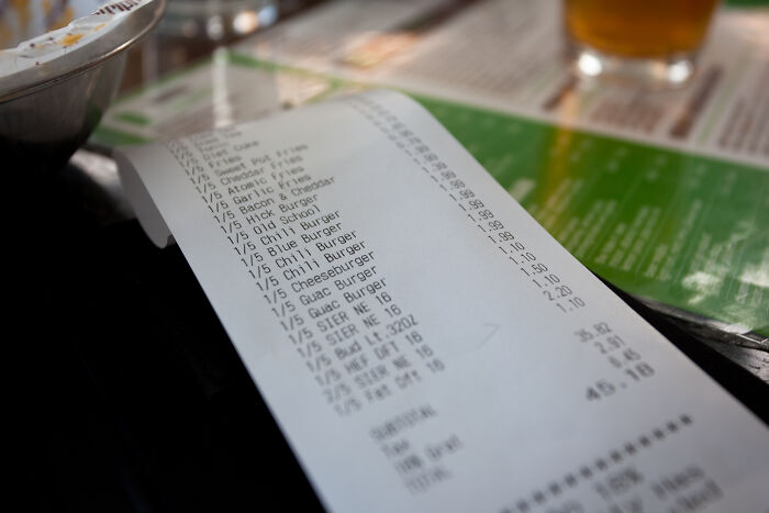 Restaurant receipt listing items and prices on a table, symbolizing gradually disappeared practices unnoticed by people.