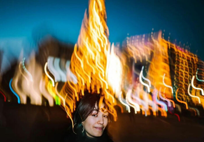 Street life captured with colorful, blurred lights and a person in the foreground, showcasing urban vibrancy.