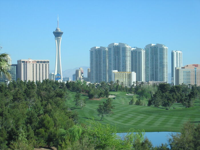 Golf course with a city skyline in the background, showcasing one of the breathtaking courses golfers travel to worldwide.