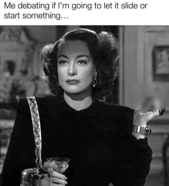 A woman in a vintage setting holding a glass, contemplating with a sarcastic expression, embodying witchcraft vibes.