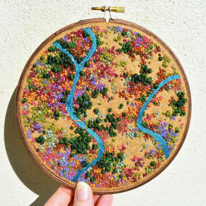 Colorful landscape embroidery by Victoria Rose Richards with vibrant threads depicting nature in a circular hoop.