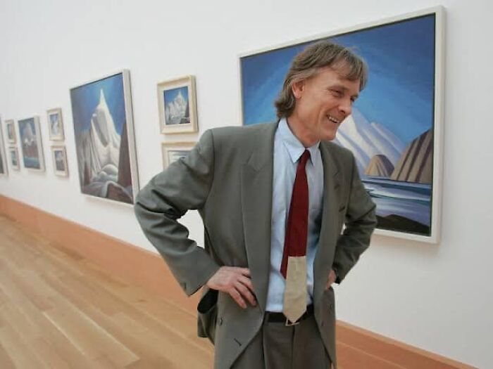 Man in a suit in an art gallery, illustrating wealth reflecting the richest people having more money than most countries.