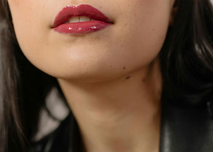 Close-up of a woman's lips with red lipstick, showcasing beauty tips.