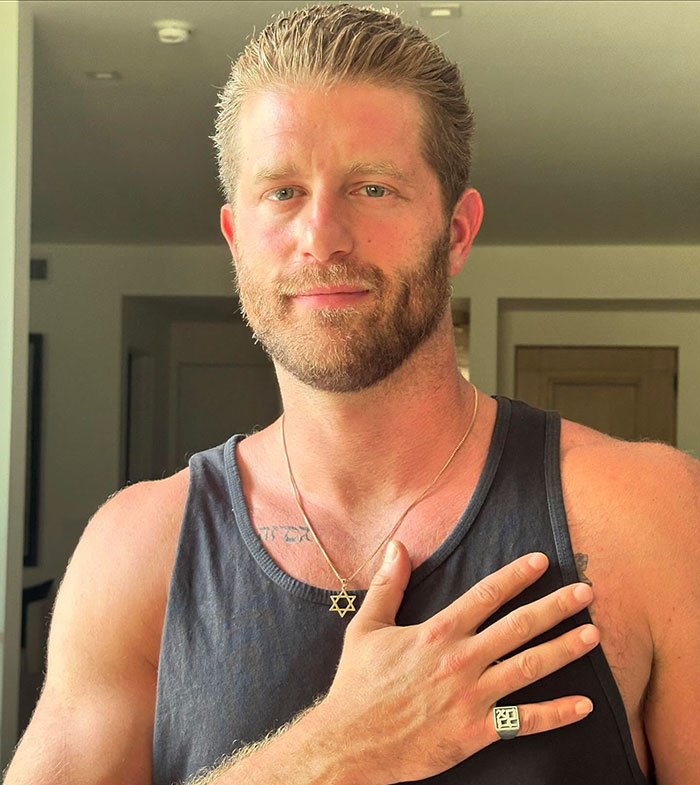 Man in a black tank top with a Star of David necklace and ring, related to 'Snow White' movie discussion. Man in a black tank top with a Star of David necklace and ring, related to 'Snow White' movie discussion.