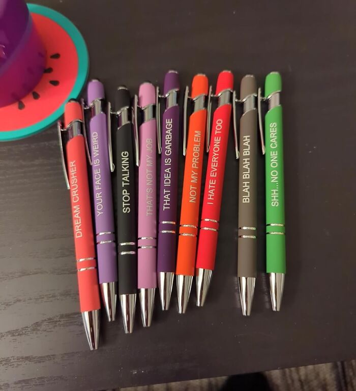 Colorful pens with humorous office sayings on a desk, related to office Olympics.
