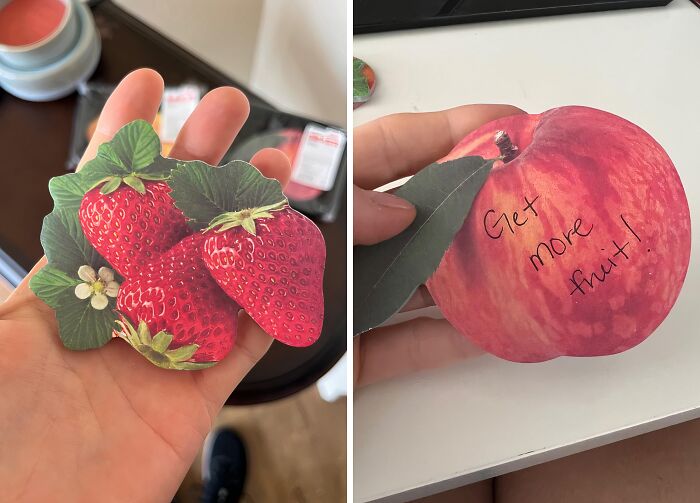 Hand holding fruit-shaped notes for Office Olympics activity; strawberries and apple with "Get more fruit!" message.