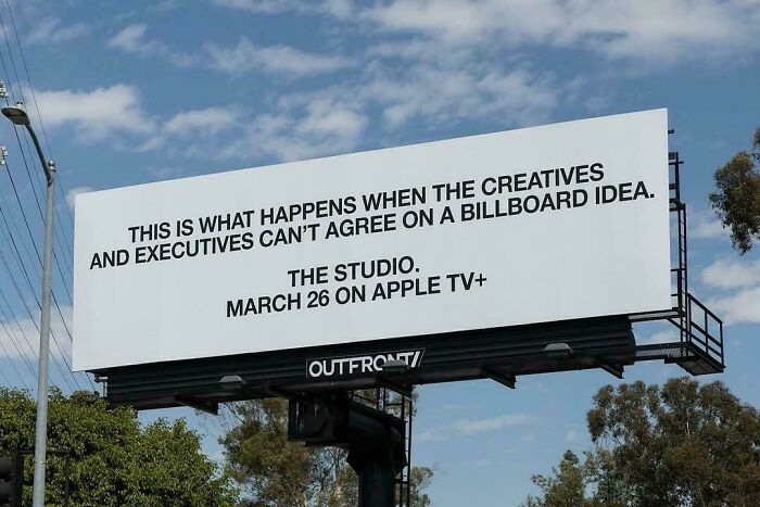 Billboard with bold text about creatives and executives disagreeing on an idea, showcasing smart and cool design creativity.