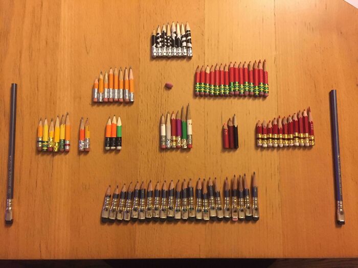 Pencils arranged by size, showing things used over time on a wooden table.