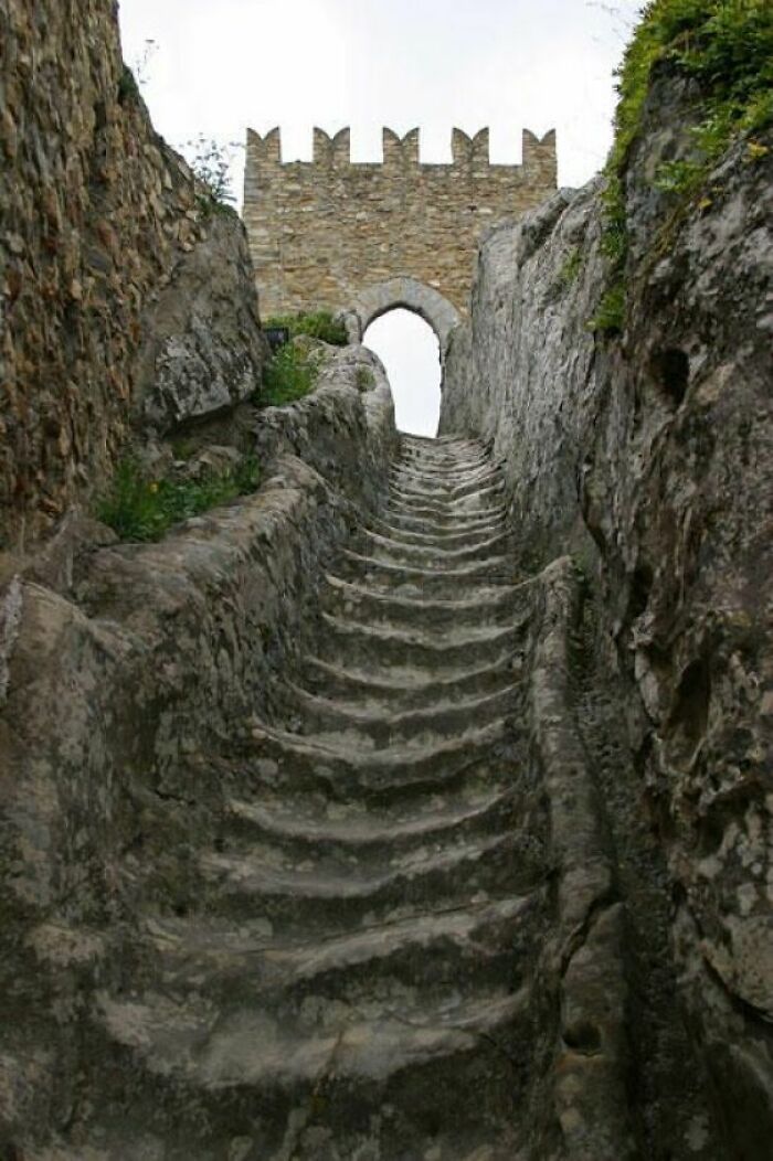 Stone steps carved into a rocky path, leading to an ancient archway, showcasing things used over time in architecture.
