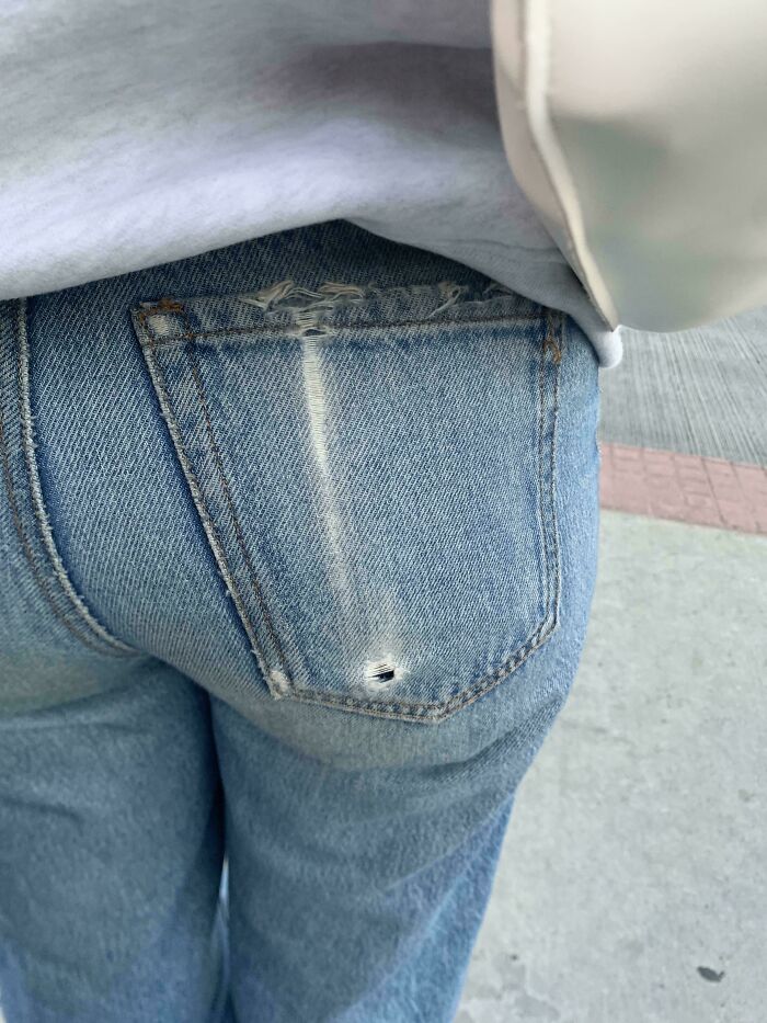Close-up of worn blue jeans with frayed pocket and small hole, illustrating things used over time.