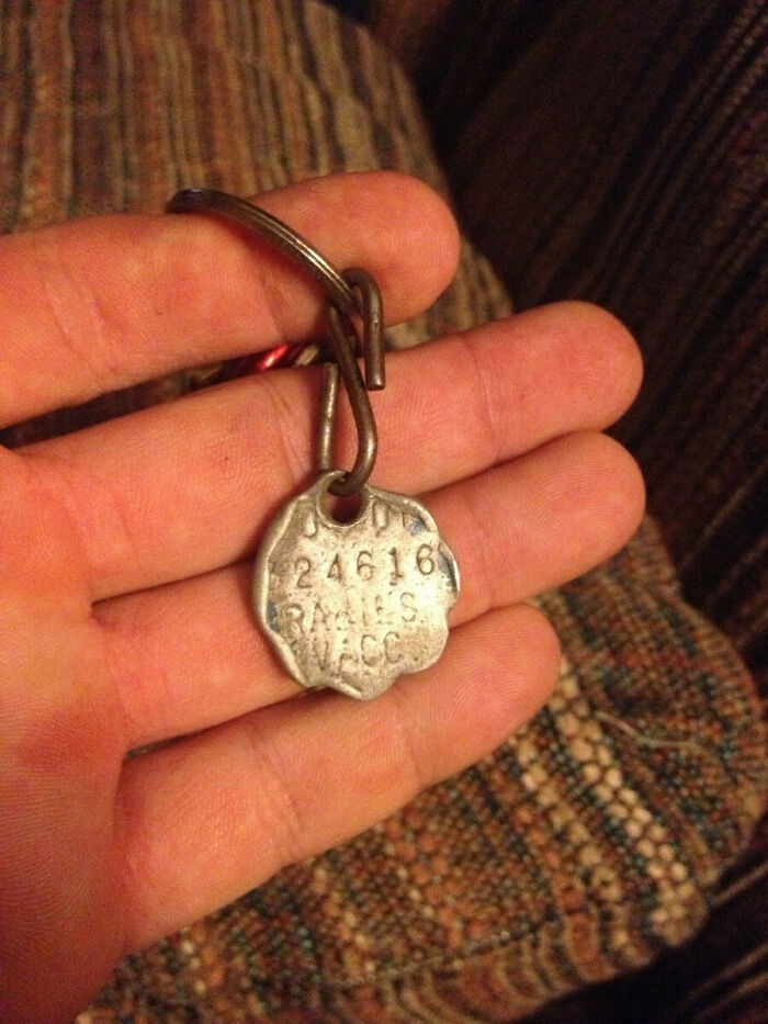 Hand holding a vintage metal tag with engravings, representing the concept of time vs. things.
