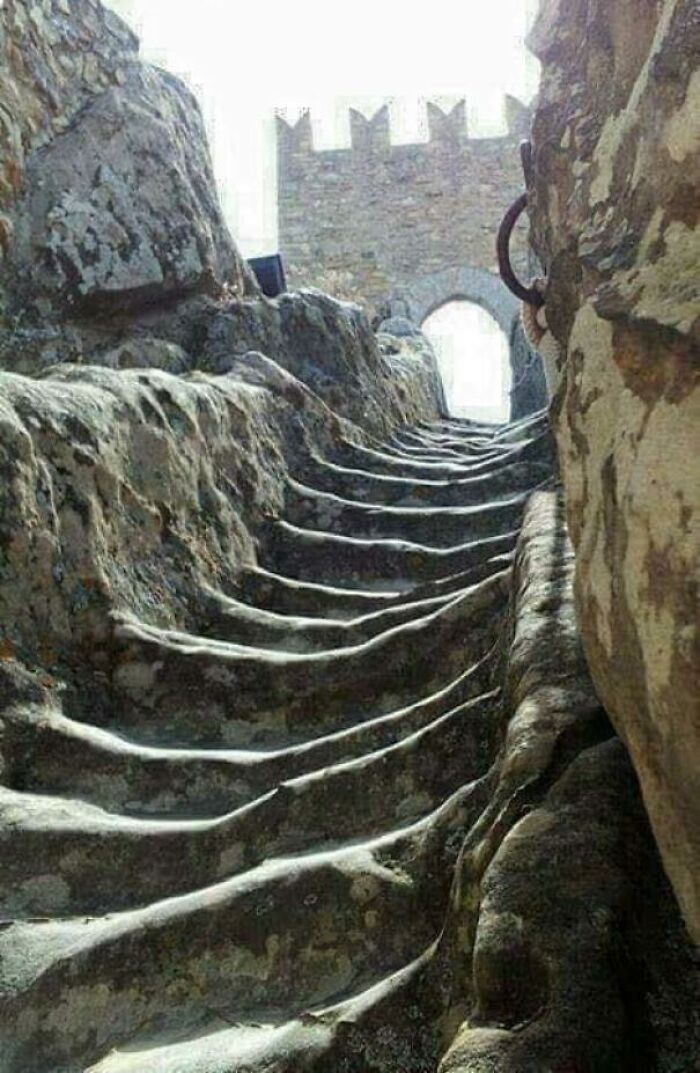 Weathered stone steps leading to an ancient archway, illustrating the erosion of time on things.
