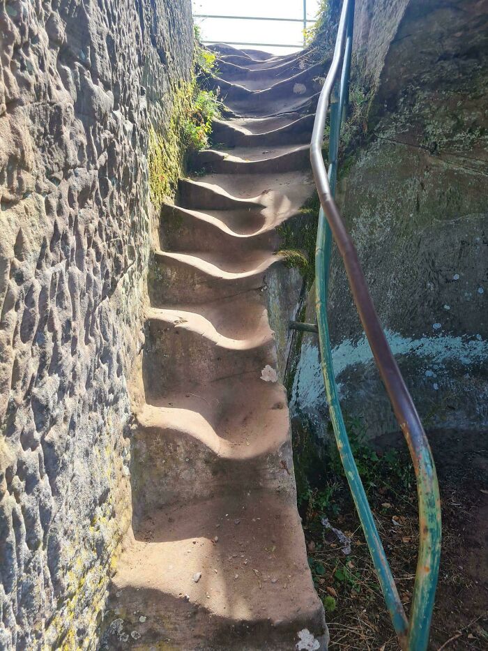 Worn stone steps with a metal railing, illustrating the impact of time on things in an outdoor setting.