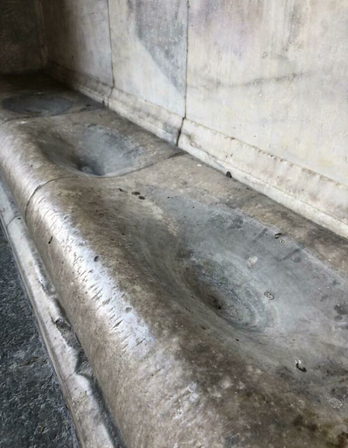 Worn marble bench showing the passage of time vs. things, with smooth, concave surfaces reflecting heavy use.