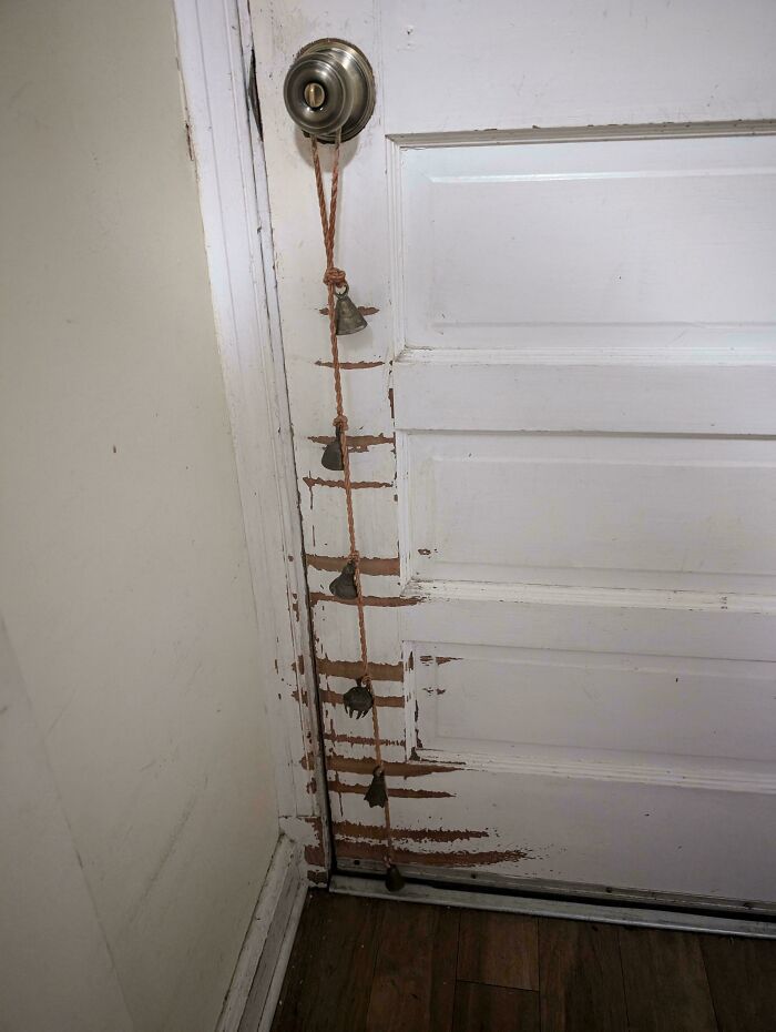 Worn white door with scratches and a bell rope hanging, depicting signs of time versus things enduring wear.