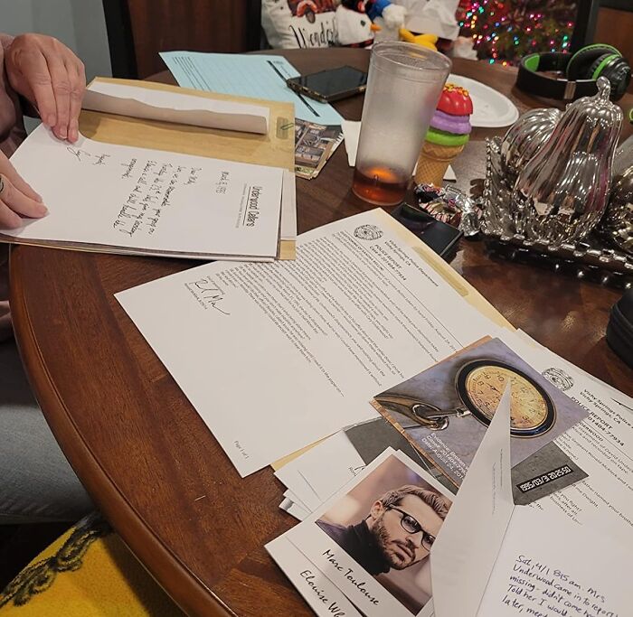 Hands writing a letter on a cluttered table, symbolizing the importance of digital detox and offline activities.
