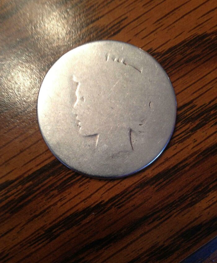 Coin close-up on wooden table, featuring worn-out engraving, illustrating the theme of time vs. things.