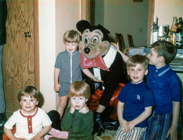 Children posing with a person in a vintage cartoon mascot costume, a candid glimpse into the past not found in history books