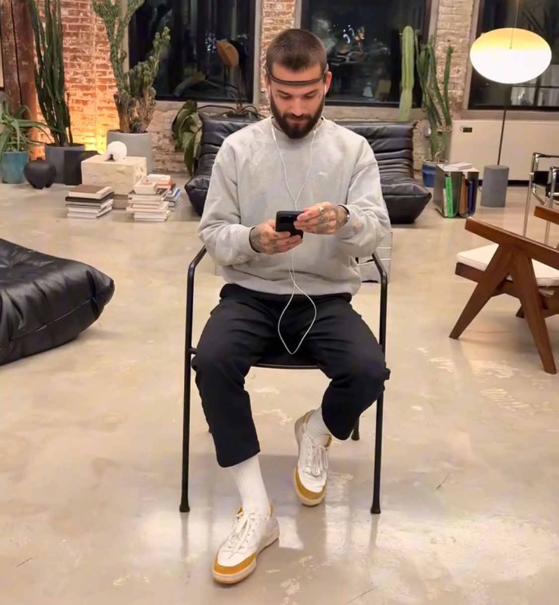 Man seated with brain activity headband, using a smartphone in a modern studio, exploring unique brain activity tattoo concept. Man seated with brain activity headband, using a smartphone in a modern studio, exploring unique brain activity tattoo concept.