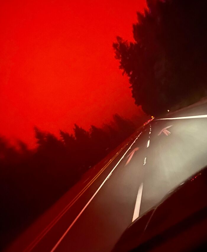 A road under a red sky, showcasing nature's powerful and terrifying beauty.