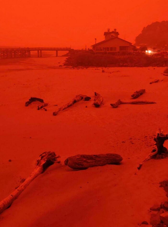 Red sky over deserted beach and building, illustrating nature's powerful and terrifying impact.