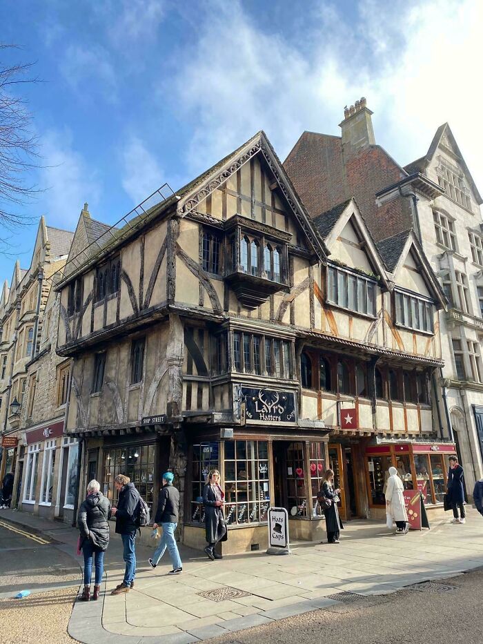 Timber-framed historic building with bay windows and intricate architectural feats on a busy street with pedestrians.