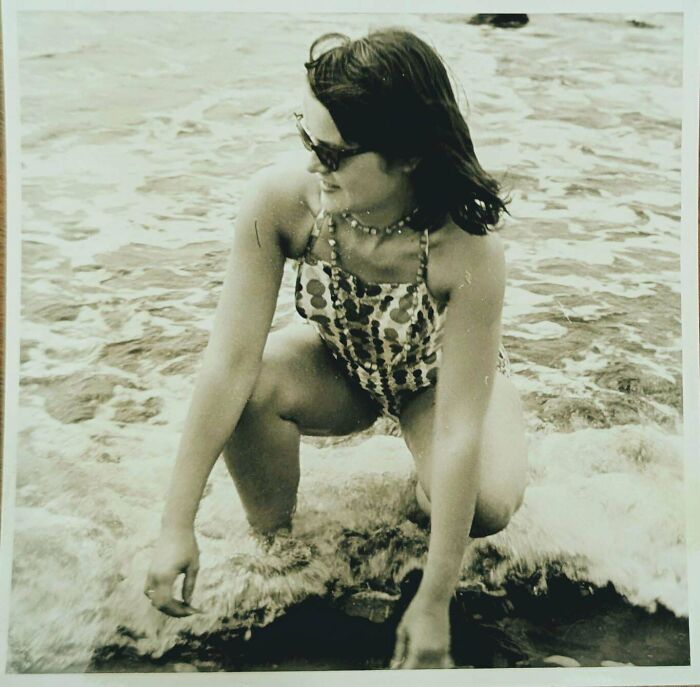 Vintage candid glimpse of a woman in a patterned swimsuit enjoying the ocean waves in a unique moment from the past.