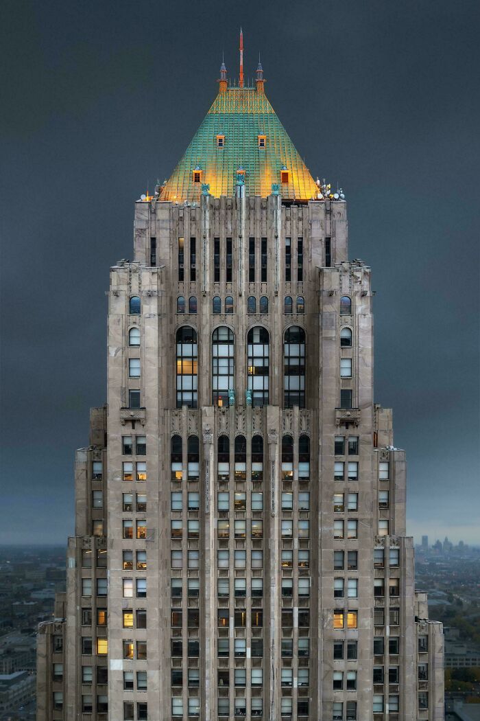 Impressive architectural feat featuring a tall building with detailed stonework and a greenish illuminated rooftop.