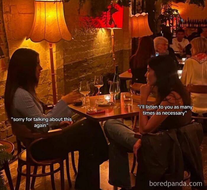 Two women chatting at a cozy restaurant, surrounded by warm lighting, wine glasses on the table.
