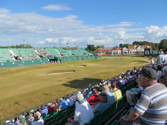 Spectators watch a golf game at a scenic course, highlighting breathtaking golfing travel destinations.