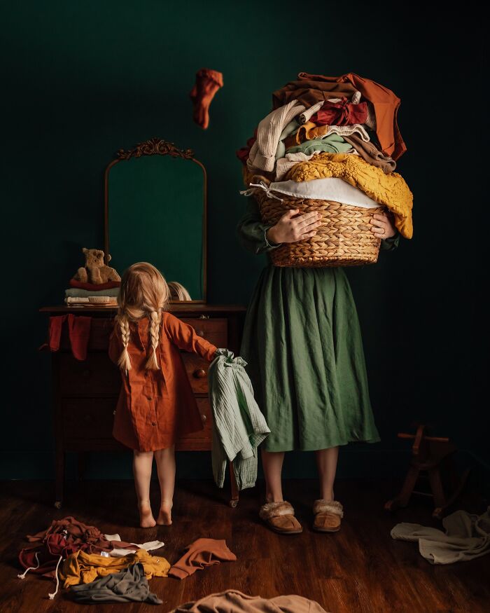 Mother holding laundry basket, while child in orange dress picks up clothes, capturing childhood magic and nostalgia.
