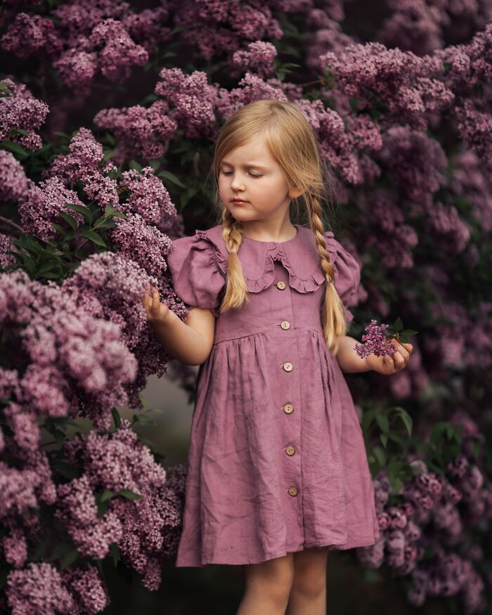 A child exploring vibrant lilacs, capturing the magic of childhood through a mother’s lens.