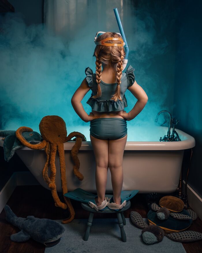 Child in a snorkel looking at a smoky bath, capturing the magic of childhood with stuffed sea creatures nearby.