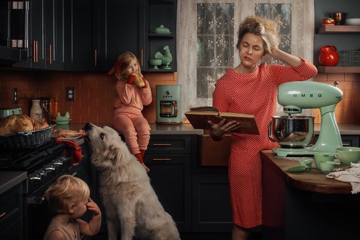 Mother capturing childhood magic in cozy kitchen scene, with kids and a dog, as she reads a book.