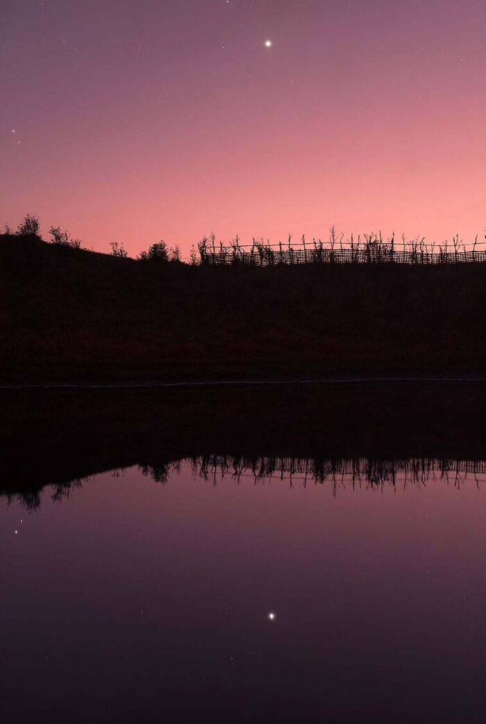 Twilight sky reflected in water, showcasing astrophotography with a single bright star above the horizon.