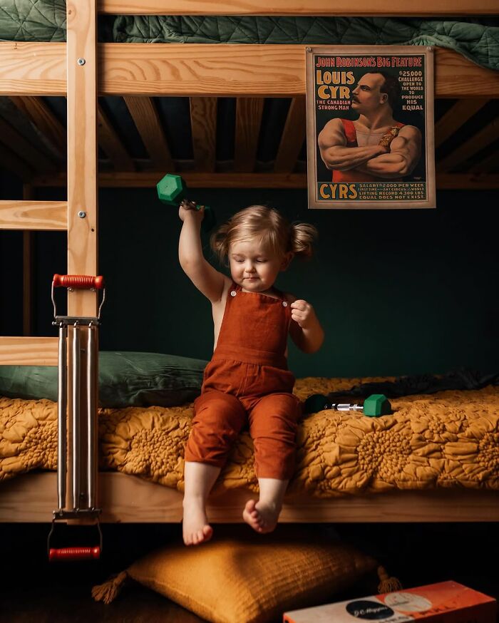 Child modeling strength with a dumbbell, embodying the magic of childhood, while sitting on a bunk bed.