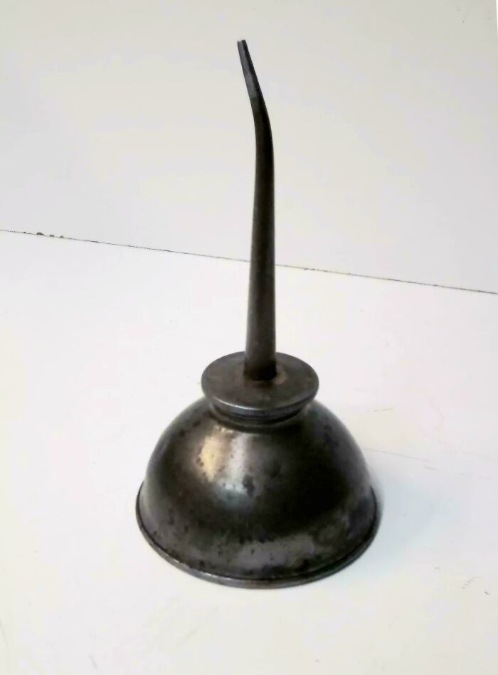 Old metal oil can with a curved spout sitting on a white surface, a nostalgic item from people who realized they’re old now.