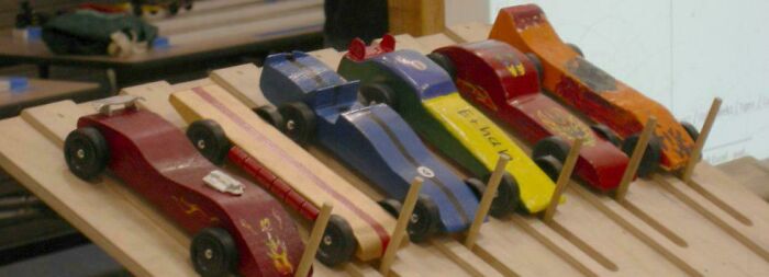 Wooden race cars lined up on a track, evoking nostalgic memories for people realizing they’re old now.